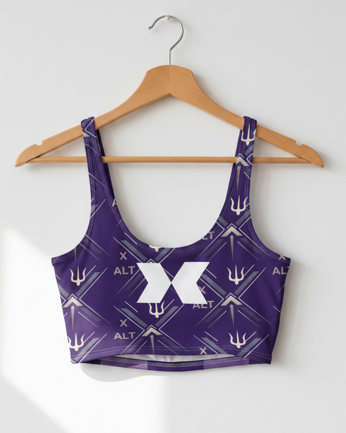 A purple sports bra with a white geometric trident pattern and a large white 'X' logo on the front, hanging on a wooden hanger against a light gray wall.
