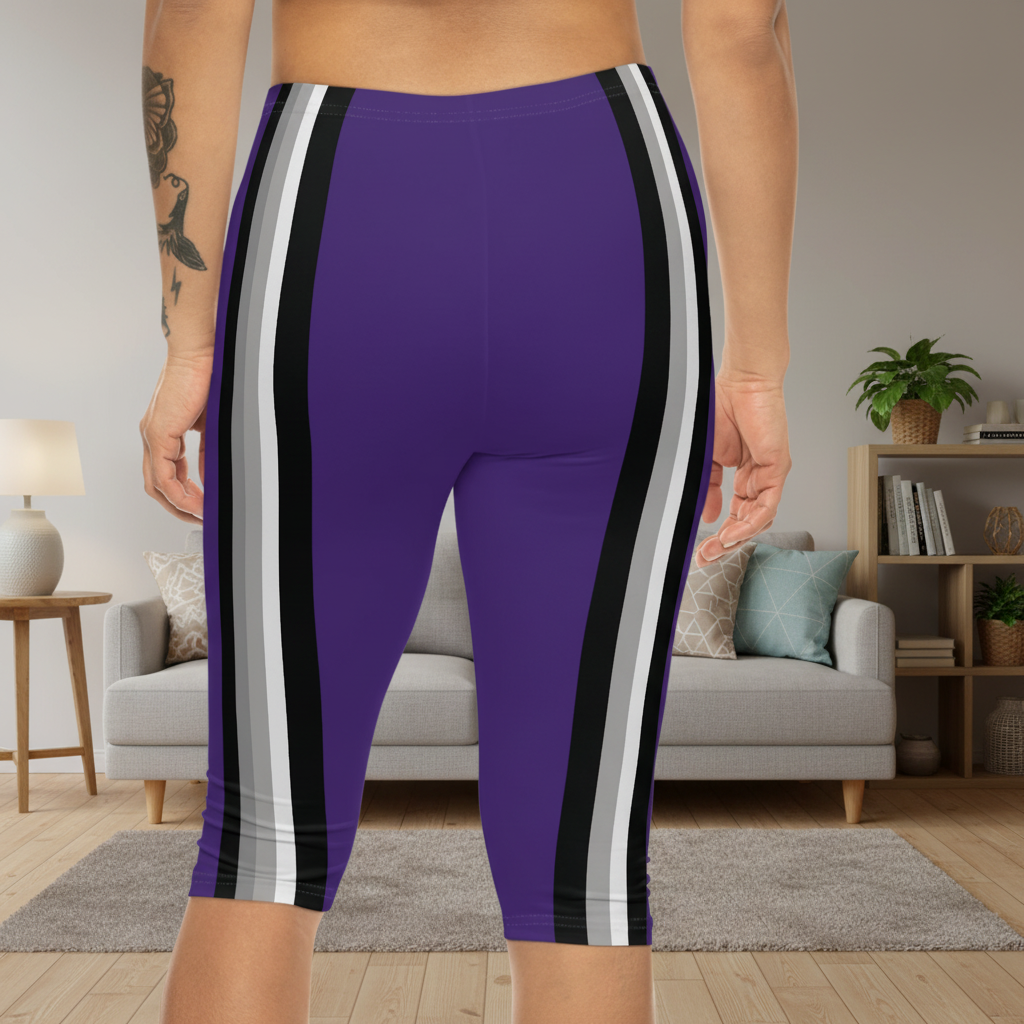 A person shown from the back wearing purple fitted biker shorts with bold vertical side stripes in black, white, and gray, standing in a living room with a sofa and shelves in the background.